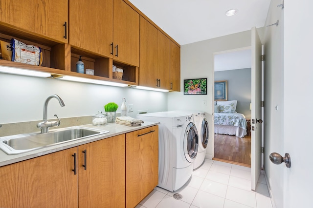 washroom with independent washer and dryer, hookup for a washing machine, light tile flooring, sink, and cabinets