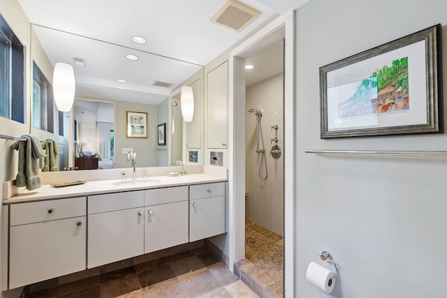 bathroom with tiled shower, tile floors, and vanity with extensive cabinet space