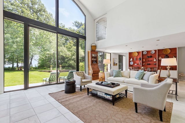 tiled living room featuring a towering ceiling and a wall of windows