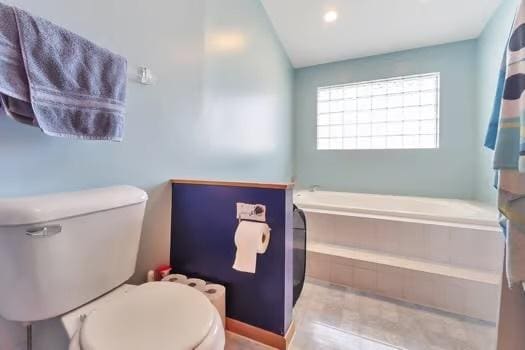 bathroom with toilet and a tub to relax in