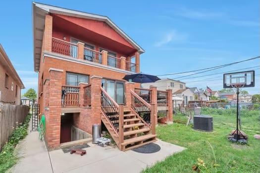 back of house featuring central AC unit, a yard, and a balcony