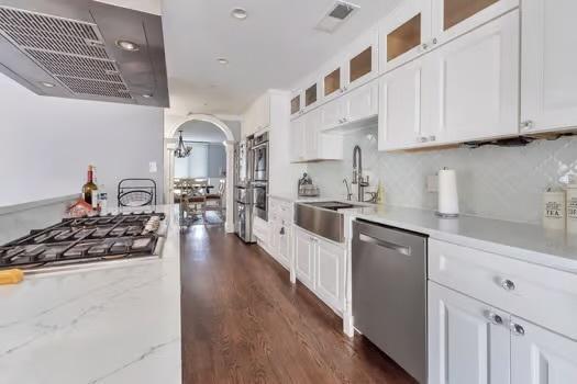 kitchen featuring ventilation hood, appliances with stainless steel finishes, light stone countertops, white cabinets, and sink