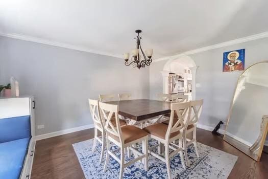 dining room with dark hardwood / wood-style floors, an inviting chandelier, and ornamental molding