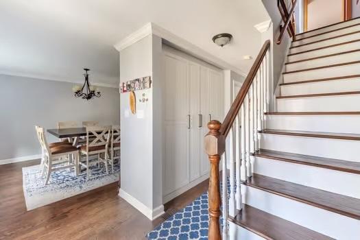 stairs featuring a notable chandelier, crown molding, and hardwood / wood-style flooring