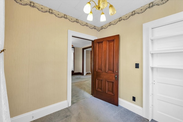 hallway with carpet flooring and an inviting chandelier