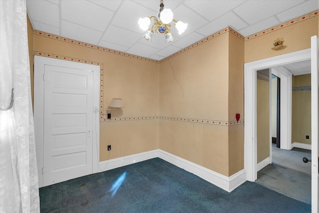 carpeted spare room with a paneled ceiling and a notable chandelier