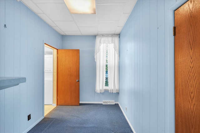 empty room featuring carpet flooring and wooden walls