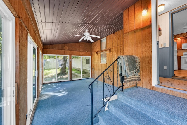 staircase featuring lofted ceiling, wood walls, and ceiling fan