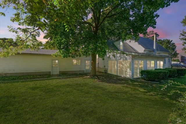 back house at dusk featuring a yard