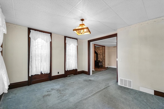 carpeted empty room featuring a wood stove