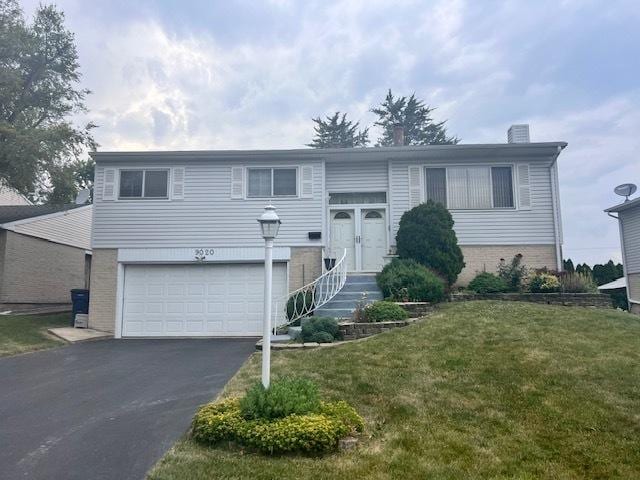 split foyer home with brick siding, entry steps, a front yard, a garage, and driveway