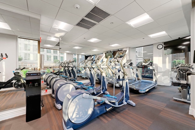 exercise room featuring dark colored carpet and a paneled ceiling