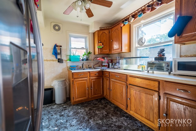 kitchen featuring ceiling fan, stainless steel fridge, sink, and tile walls