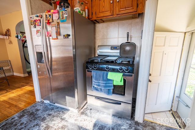 kitchen featuring light wood-type flooring, appliances with stainless steel finishes, and backsplash