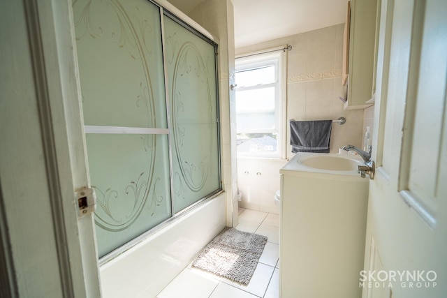 full bathroom featuring vanity, tile patterned floors, bath / shower combo with glass door, toilet, and tile walls