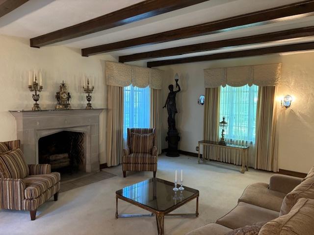 carpeted living room featuring beam ceiling, a high end fireplace, and radiator heating unit