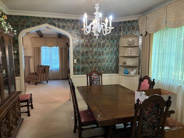 dining area featuring crown molding, carpet, and a notable chandelier