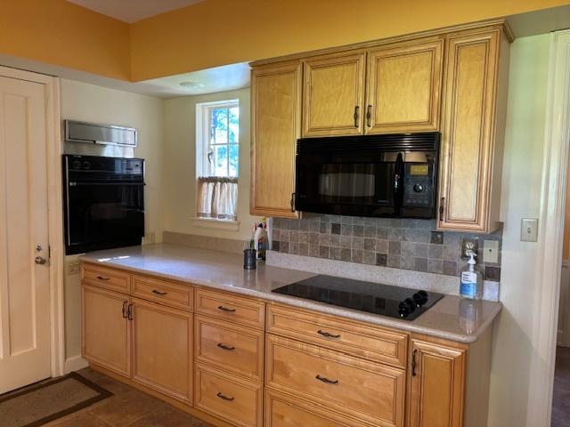 kitchen with tasteful backsplash, dark tile patterned floors, and black appliances