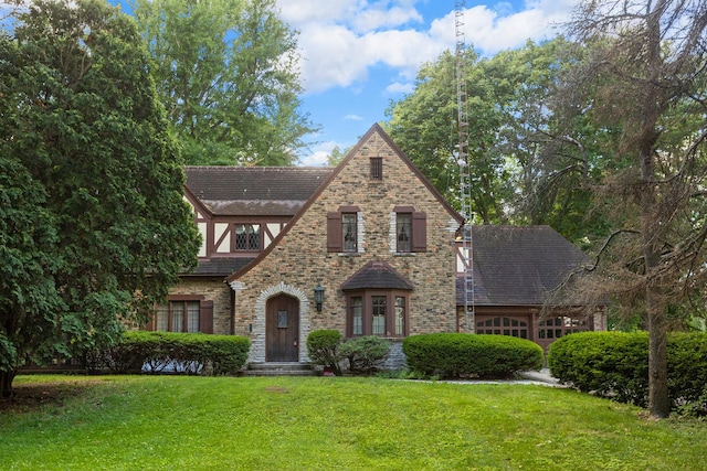 tudor-style house featuring a garage and a front lawn