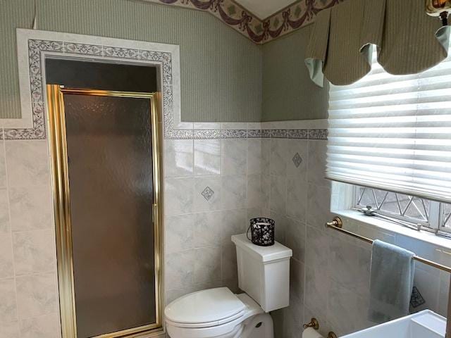 bathroom with walk in shower, toilet, and tile walls