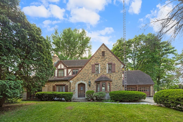 english style home featuring a garage and a front lawn