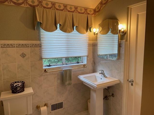 bathroom with toilet and tile walls