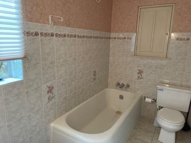 bathroom featuring tile walls, tile patterned floors, and toilet