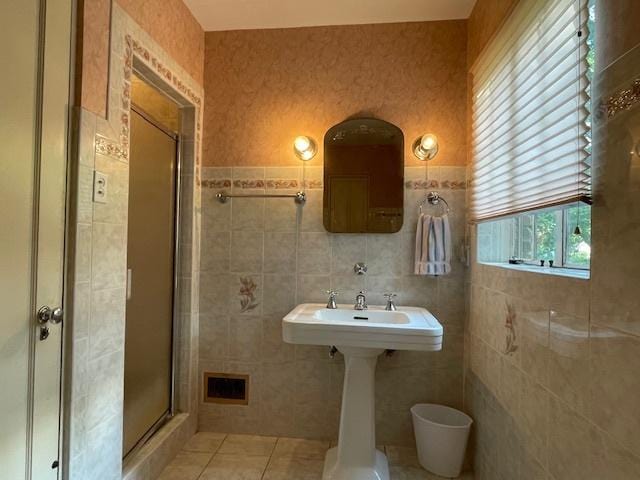 bathroom with tile patterned flooring, tile walls, and a shower with shower door