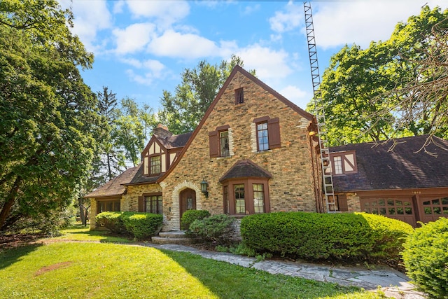 english style home featuring a garage and a front yard