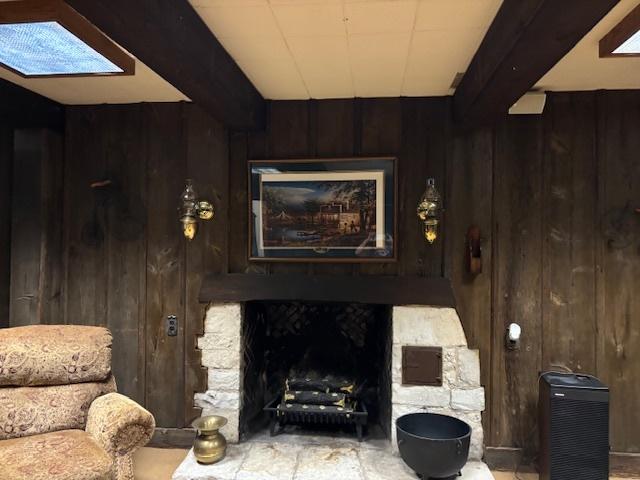 living room with wooden walls, a skylight, and beam ceiling