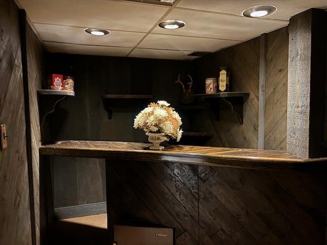 bar featuring a paneled ceiling and wood walls