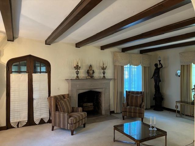 living room featuring a premium fireplace, light colored carpet, french doors, and beamed ceiling