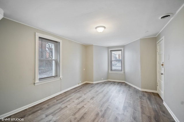 empty room with crown molding and light hardwood / wood-style floors