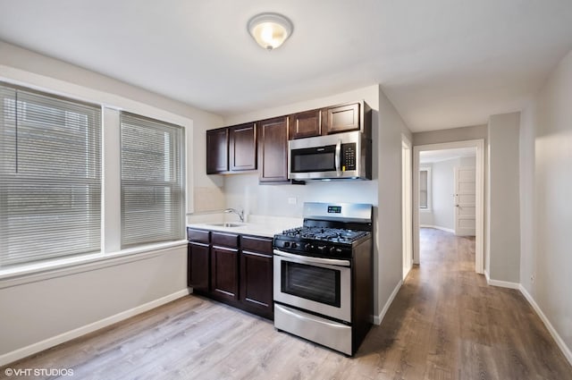 kitchen with sink, dark brown cabinets, light hardwood / wood-style flooring, and appliances with stainless steel finishes