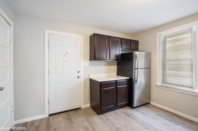 kitchen with light hardwood / wood-style flooring, stainless steel fridge, and dark brown cabinetry