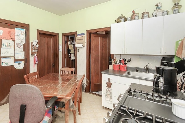 kitchen featuring white cabinetry, sink, and range