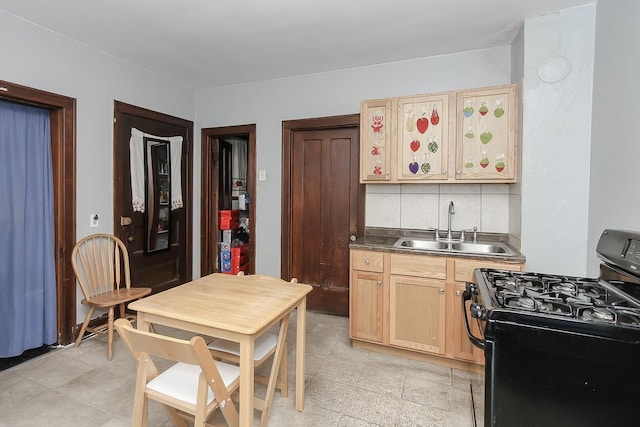 kitchen with black gas range, light brown cabinetry, sink, and backsplash