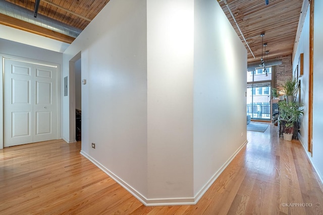 hallway with beamed ceiling, a high ceiling, light wood-type flooring, and wooden ceiling