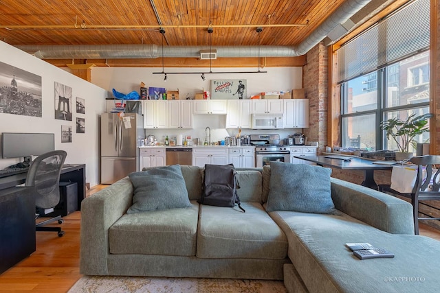 living room with brick wall, light hardwood / wood-style floors, and sink