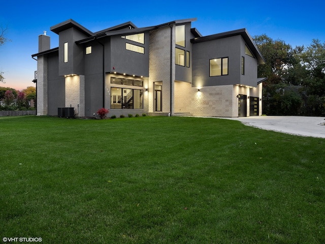 contemporary home featuring central AC, a garage, and a yard