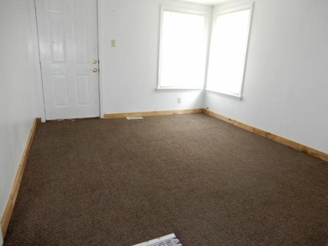 spare room featuring dark colored carpet