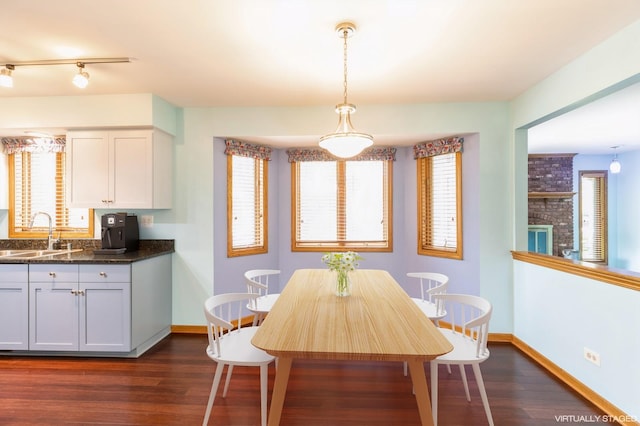 unfurnished dining area with dark wood finished floors, a sink, and baseboards