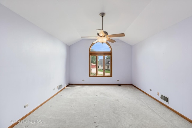 carpeted empty room with baseboards, visible vents, vaulted ceiling, and a ceiling fan