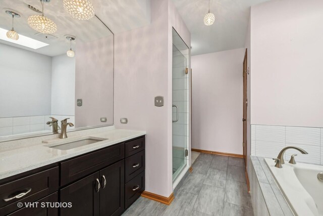 bathroom with hardwood / wood-style flooring, vanity, a skylight, and independent shower and bath