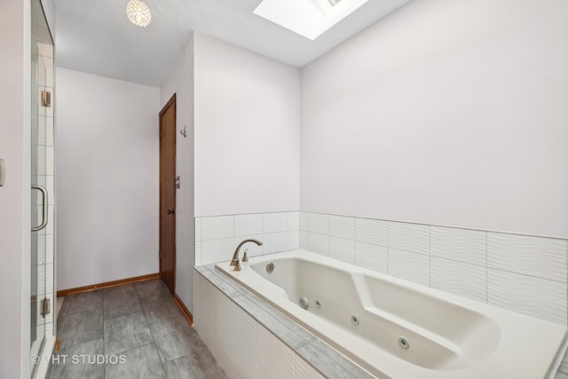 full bath featuring a jetted tub, a skylight, baseboards, and a stall shower