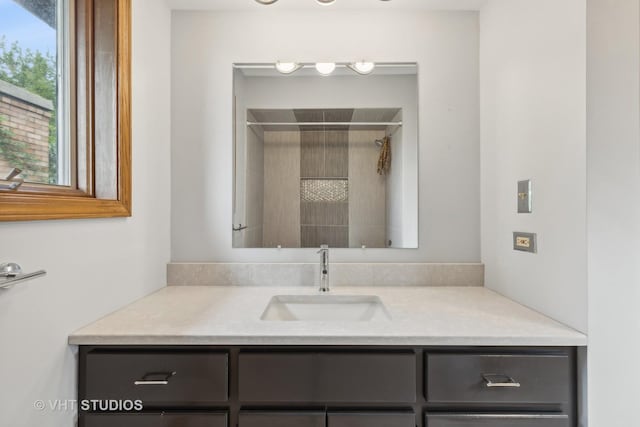 bathroom with a tile shower and vanity