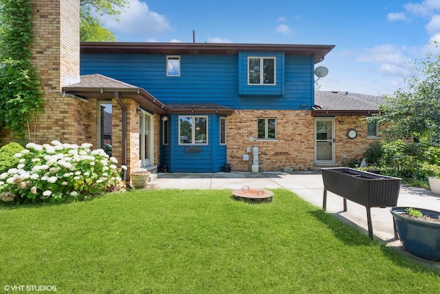 back of house with a patio area, a chimney, a lawn, and brick siding