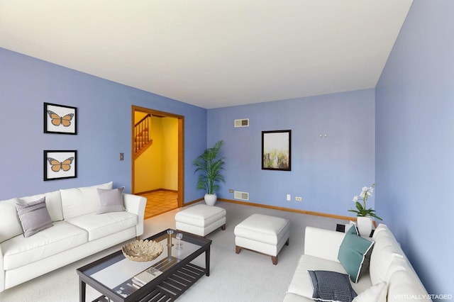 living area with carpet floors, visible vents, stairway, and baseboards