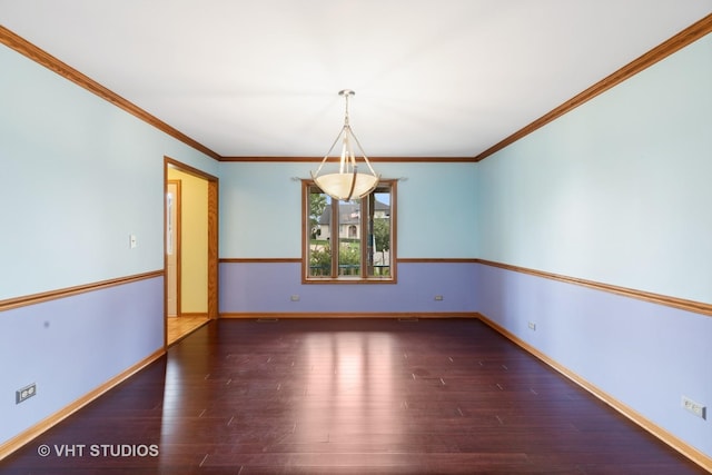 empty room featuring crown molding, baseboards, and wood finished floors