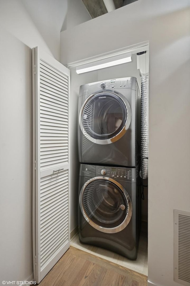 clothes washing area with stacked washing maching and dryer